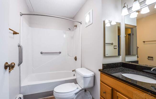 A white toilet sits next to a white bathtub in a bathroom.