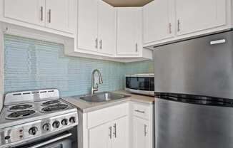 A kitchen with a stove, sink, and refrigerator.
