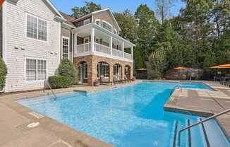 A large swimming pool in front of a two-story house.