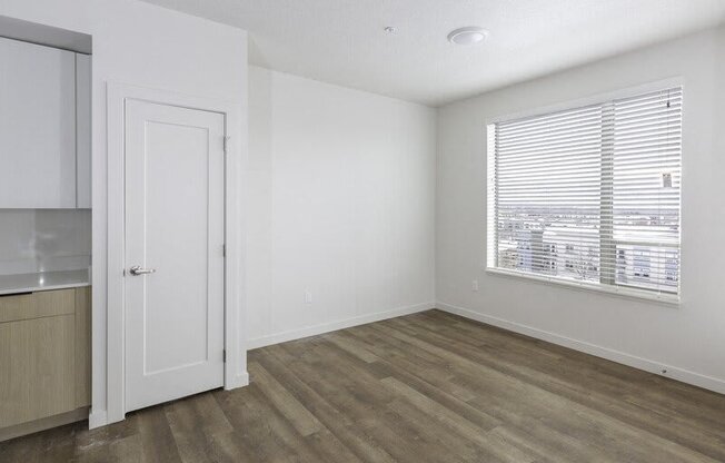 A room with a wooden floor and a window with blinds.