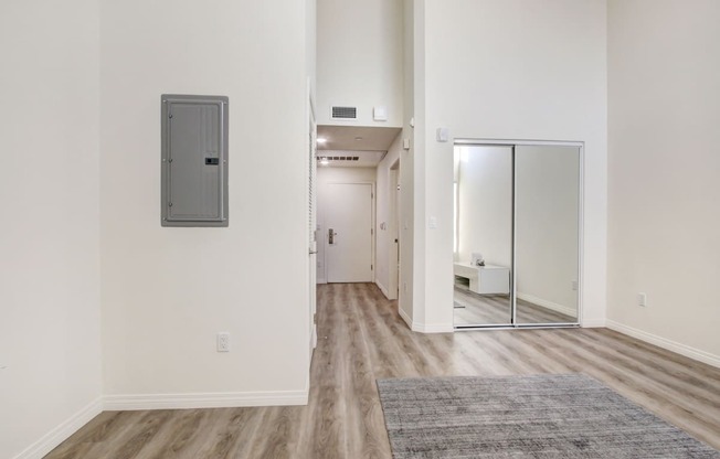 Living and sleeping area with mirrored closet doors, laminate flooring