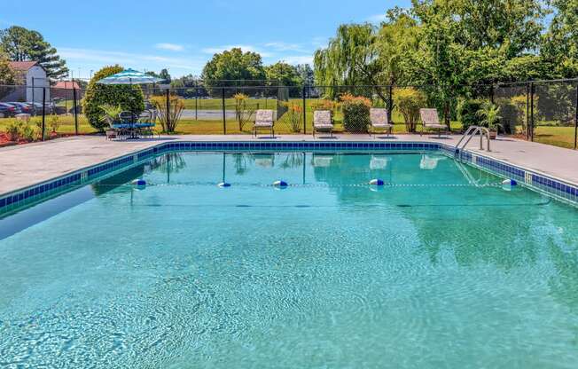 a swimming pool with two chairs and a fence around it