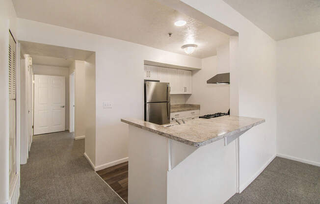 A kitchen area with a breakfast bar and a refrigerator at West Hampton Park Apartments in Elkhorn, NE 68022