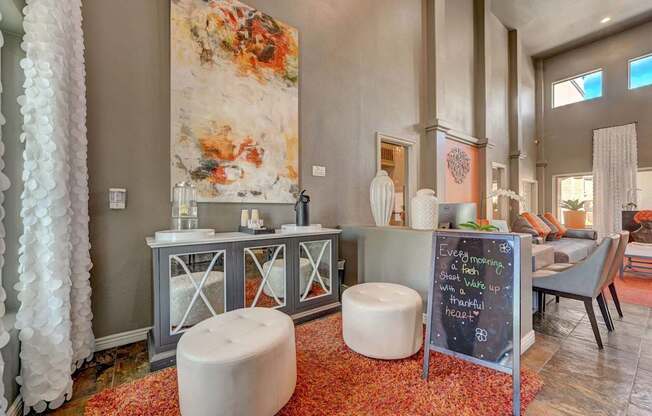 A room with a large painting on the wall and a chalkboard sign on the side table.