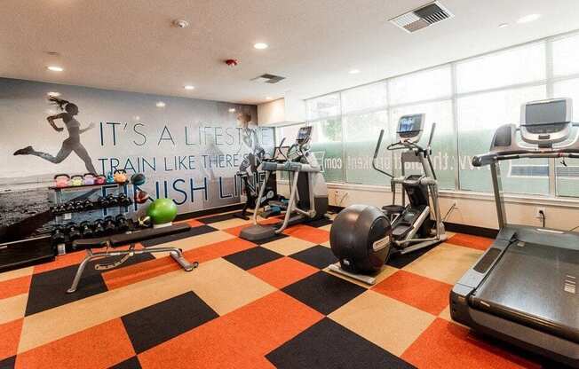 A gym with a running track and a wall mural that says "It's a lifestyle, train like there's no tomorrow".