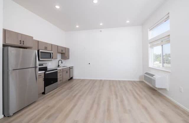 A kitchen with a refrigerator, microwave, oven, and cabinets.