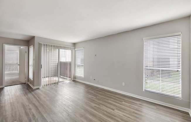 the living room of an apartment with wood flooring and a balcony
