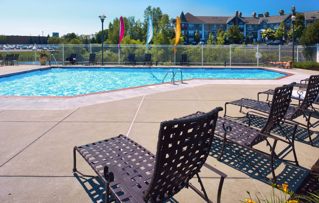 a swimming pool with patio furniture and chairs next to it