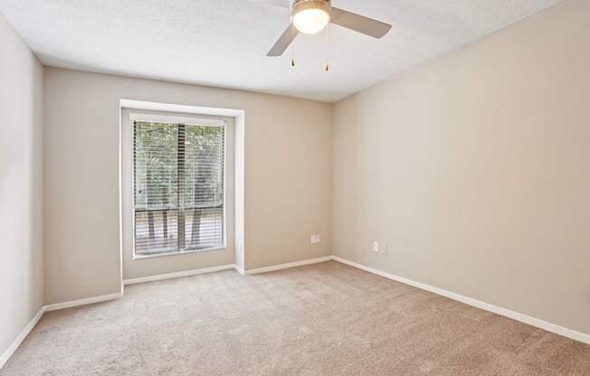 A room with a ceiling fan and a window with blinds.