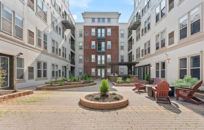 A courtyard with a brick circle in the middle and a red bench on the right.