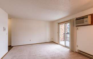 an empty living room with a sliding glass door to a balcony