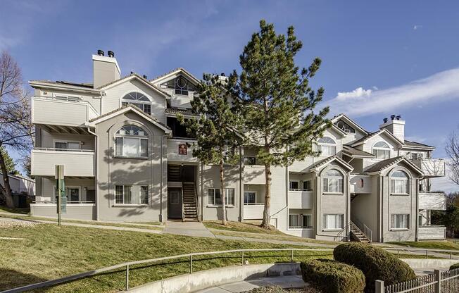 A large, multi-story residential building with a grey facade and white trim.