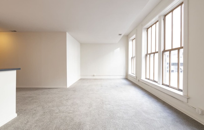 an empty room with large windows and a carpeted floor at 26 West, Managed by Buckingham Urban Living, Indianapolis