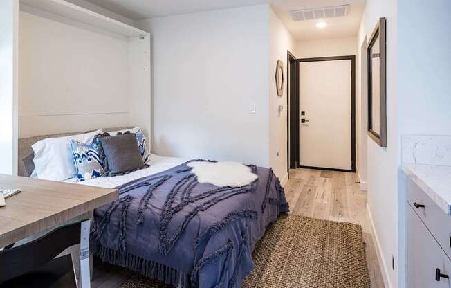 A bedroom with a bed covered in a blue blanket.