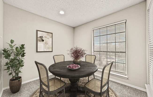 a dining room with a table and chairs and a window at Legacy Apartments in Plano, TX