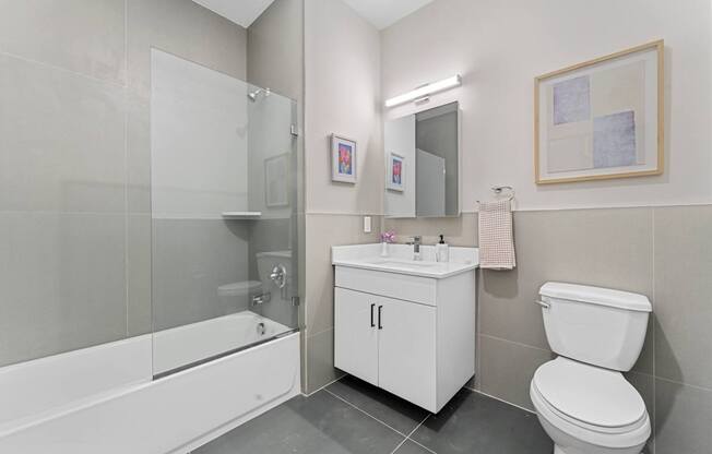A white bathroom with a toilet, sink, and shower.at 829 Garfield, Jersey City, NJ
