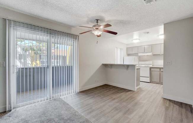 A room with a ceiling fan and sliding glass doors.