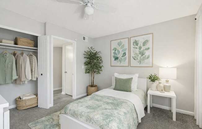 A bedroom with a bed, a nightstand, and a plant.