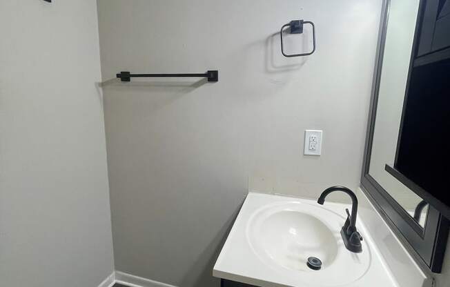 A bathroom with a white sink and black towel rack.