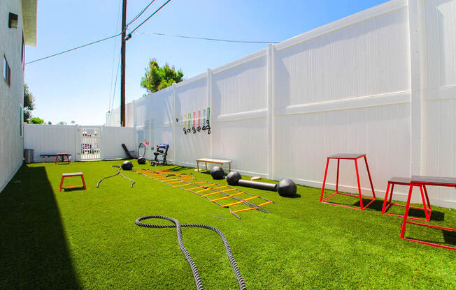 Outdoor fitness center with free weights, jump ropes, and medicine balls.