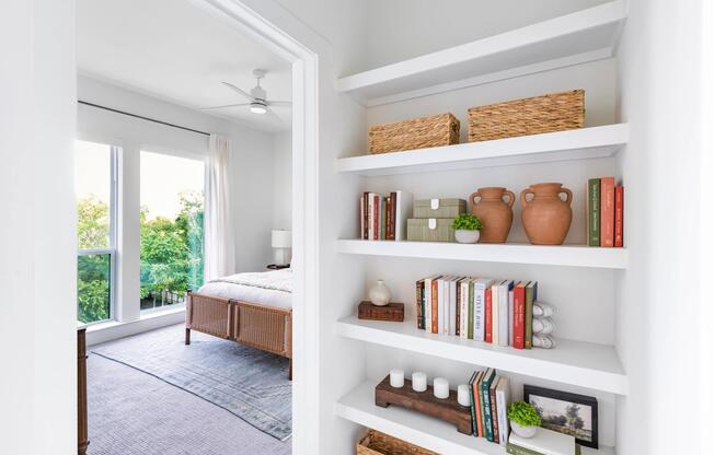 Built-in shelving with curated storage offers a thoughtful transition into a light-filled bedroom with open views and a calm, organized feel.
