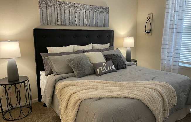 A bedroom with a large bed and a lamp on a side table.