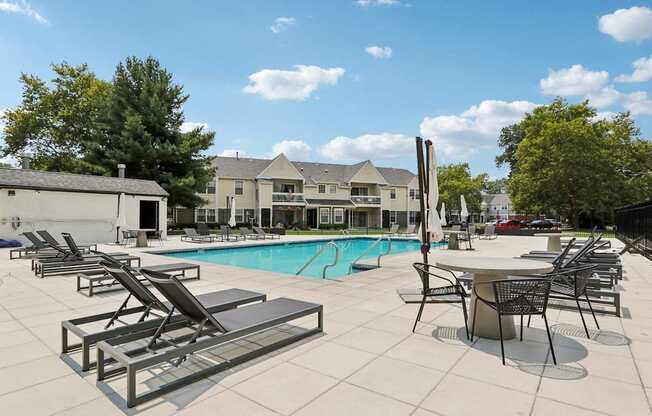 A pool with sun loungers and a table with chairs.