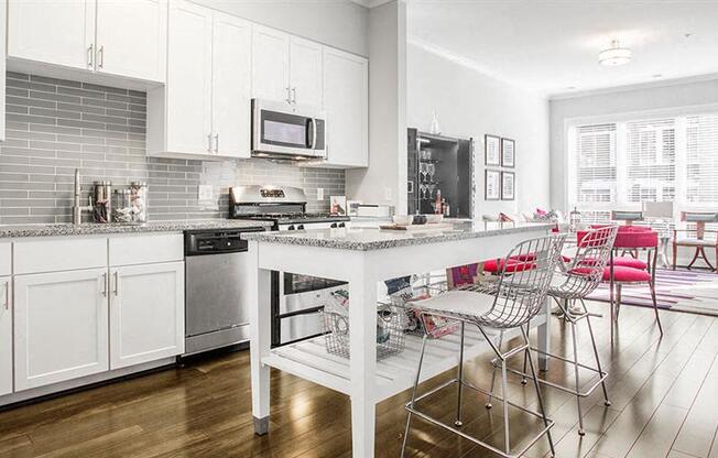 a white kitchen with a bar and chairs