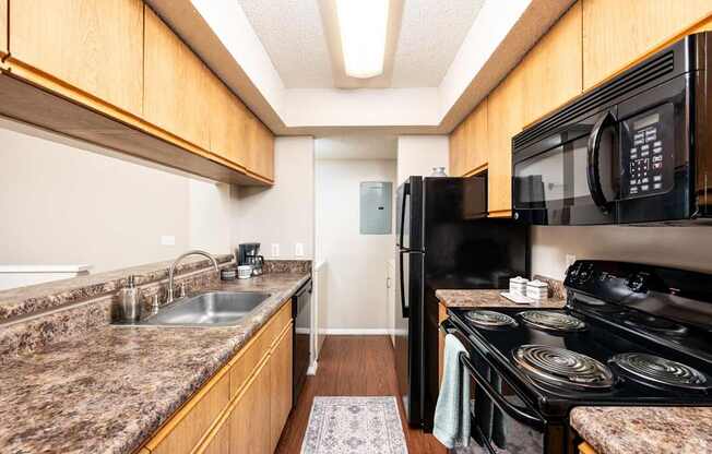 A kitchen with granite countertops and a black stove.