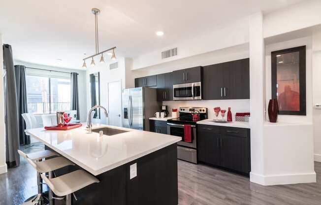 A kitchen with a ceiling light and stools and island and oven and microwave and stove and window and fridge