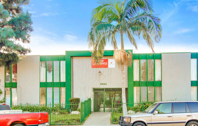 a green and white building with a palm tree in front of it