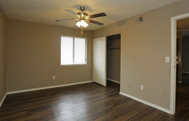 an empty living room with a ceiling fan and a door to a closet