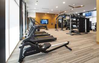 a gym with treadmills and other exercise equipment in a room with a window