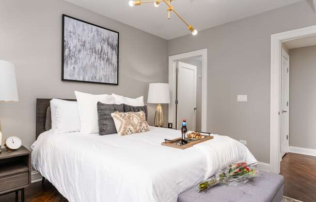 a bedroom with a white bed and a table with a bottle of wine