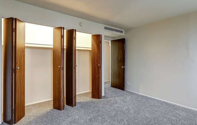 A room with a carpeted floor and four wooden doors.