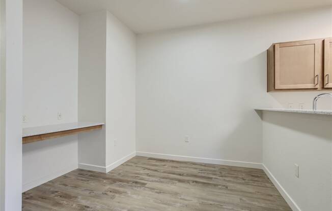 an empty room with wood flooring and a kitchen