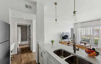 A kitchen with a white counter top and a bowl of fruit on it.