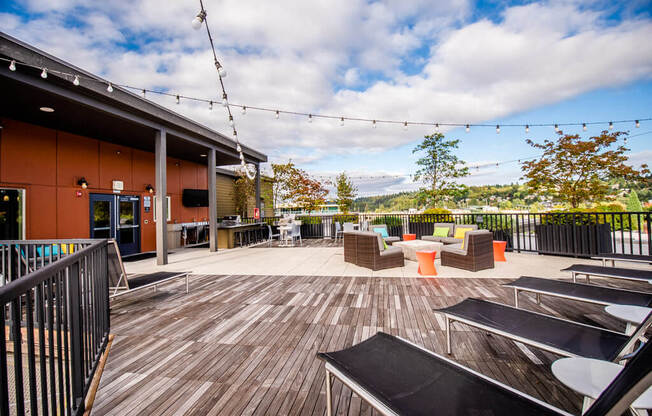 A wooden deck with chairs and tables is surrounded by a black railing. at The Platform, Kent, 98032