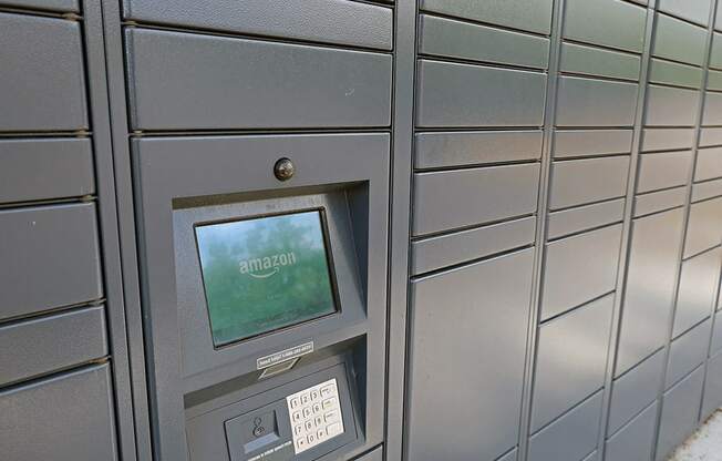 A grey mailbox with a screen showing the Amazon logo.