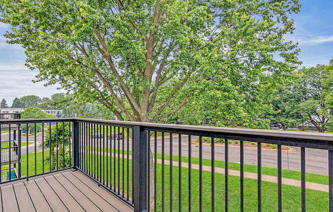 A tree is in the background of a balcony.