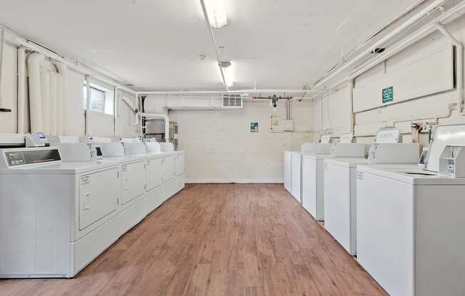 an empty laundry room with white washers and dryers