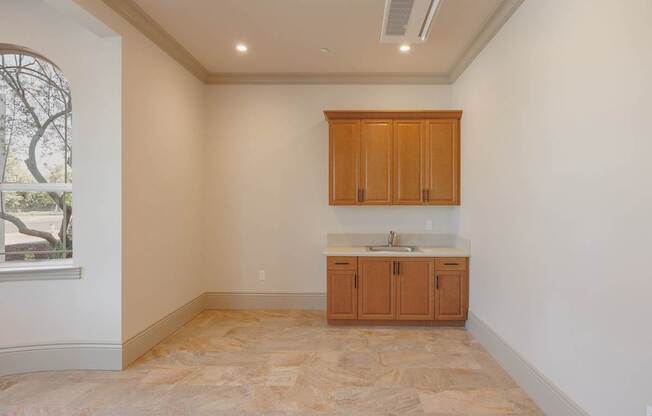 A kitchen with wooden cabinets and a marble floor.
