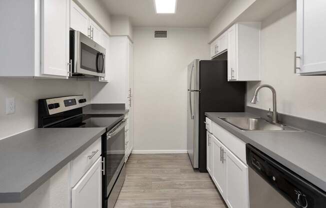 A kitchen with black appliances and white cabinets.