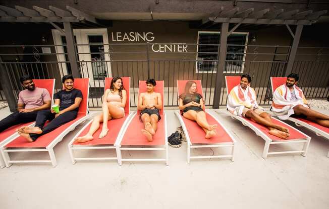 a group lounging on the pool chairs together