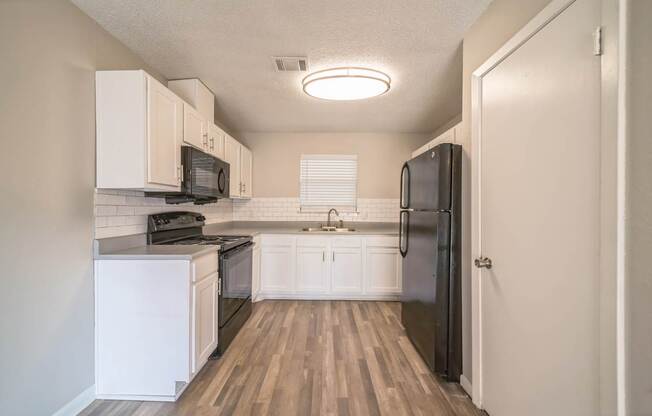 A kitchen with black appliances and white cabinets.