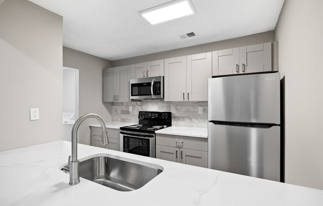 A kitchen with a stainless steel refrigerator, microwave, oven, and sink.