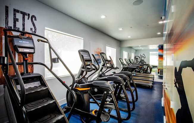 Colton Apartments A gym with treadmills and elliptical machines.