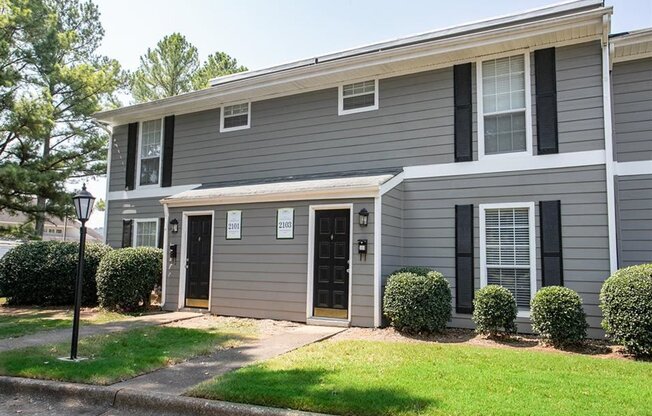 a gray house with black shutters and a lawn