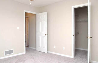 an empty bedroom with a closet and a white door
