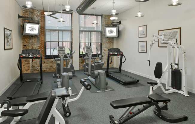 a gym with weights and exercise equipment in a room with windows at Tindeco Wharf, Baltimore, MD